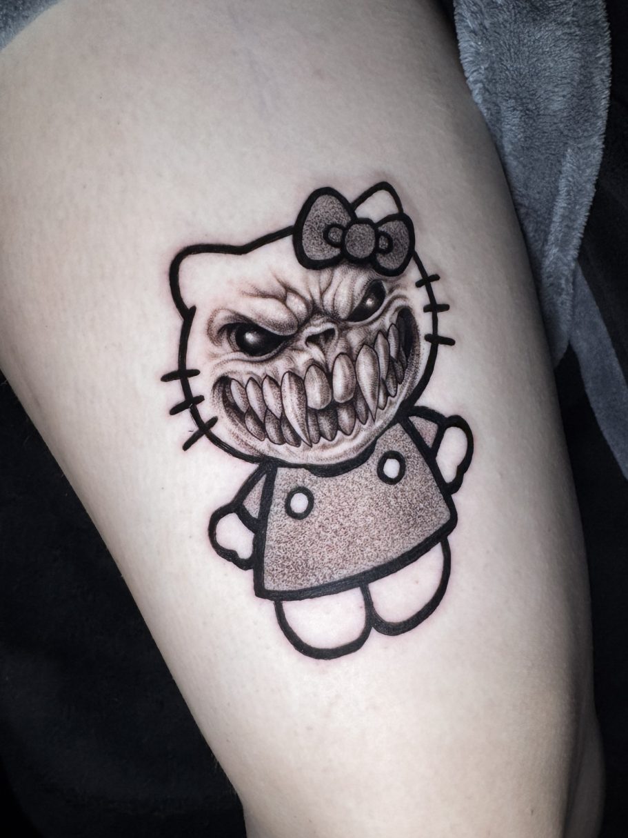 Tattoo eines grimmigen, verzerrten Katzencharakters in einem rosa Kleid mit einer Schleife
Hello Kitty monster kitty tattoo